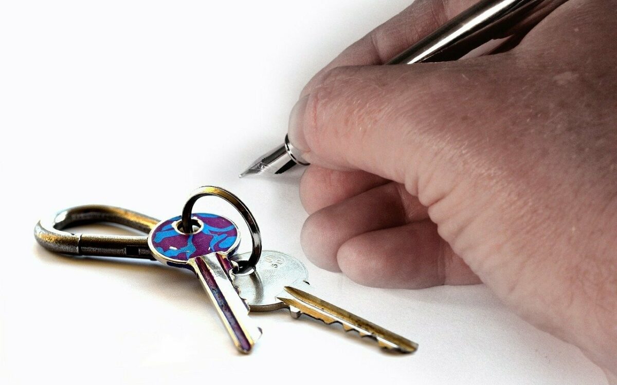 Ein Mietvertrag wird unterschrieben zu sehen ist eine Hand und ein Schluesselbund Ein Mietvertrag wird unterschrieben zu sehen ist eine Hand und ein Schluesselbund